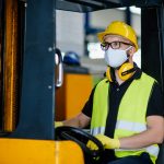 Portrait of man worker forklift driver with protective mask working in industrial factory or warehouse.